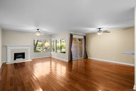 a view of an empty room with window and wooden floor