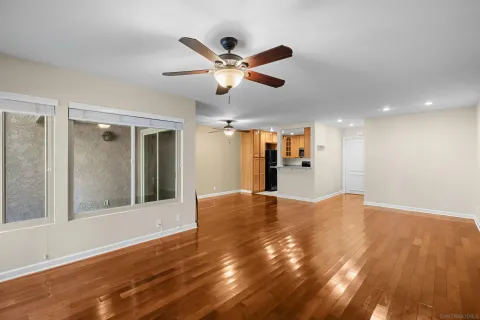 a view of empty room with wooden floor and fan