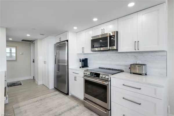 a kitchen with stainless steel appliances granite countertop white cabinets and a stove top oven