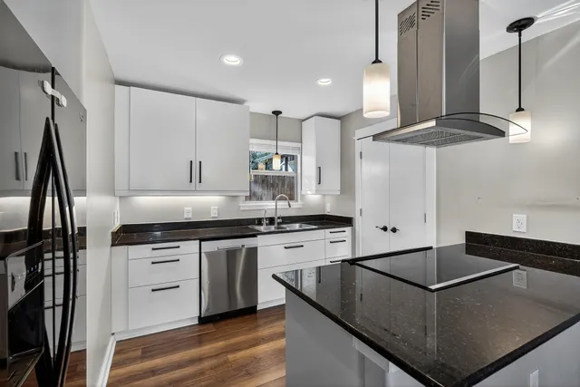 a kitchen with stainless steel appliances granite countertop a sink a stove and a refrigerator