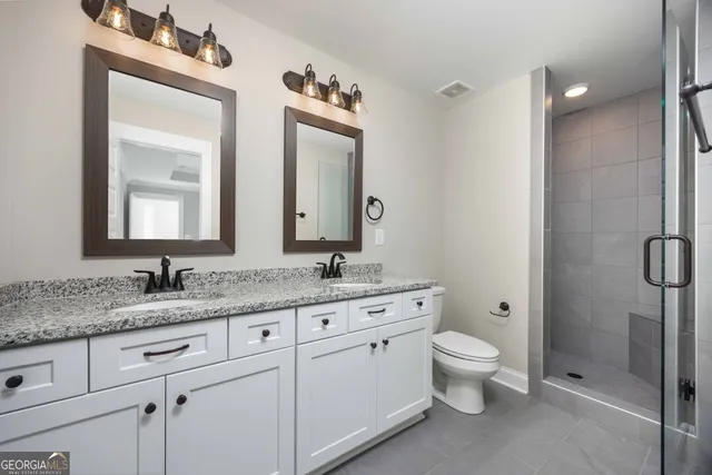 a bathroom with a granite countertop toilet sink and mirror