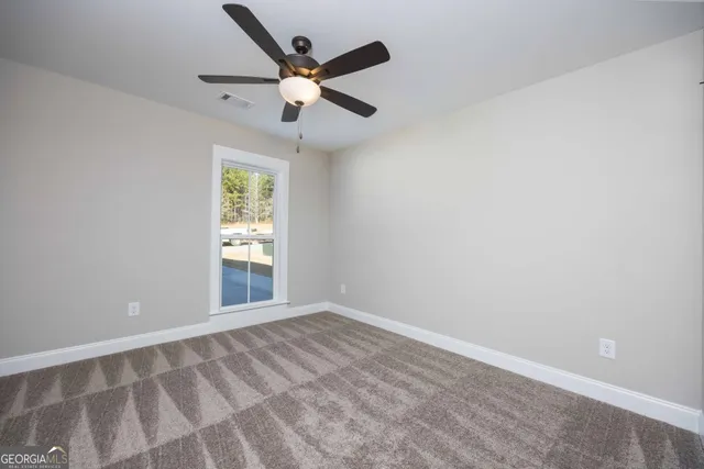 an empty room with windows and ceiling fan
