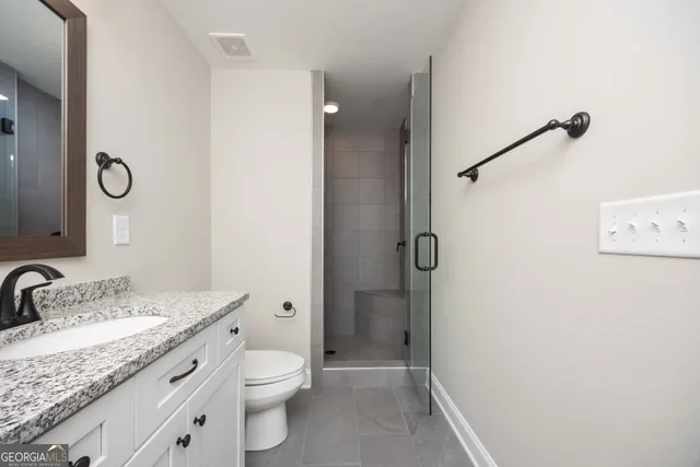 a bathroom with a granite countertop sink toilet and shower
