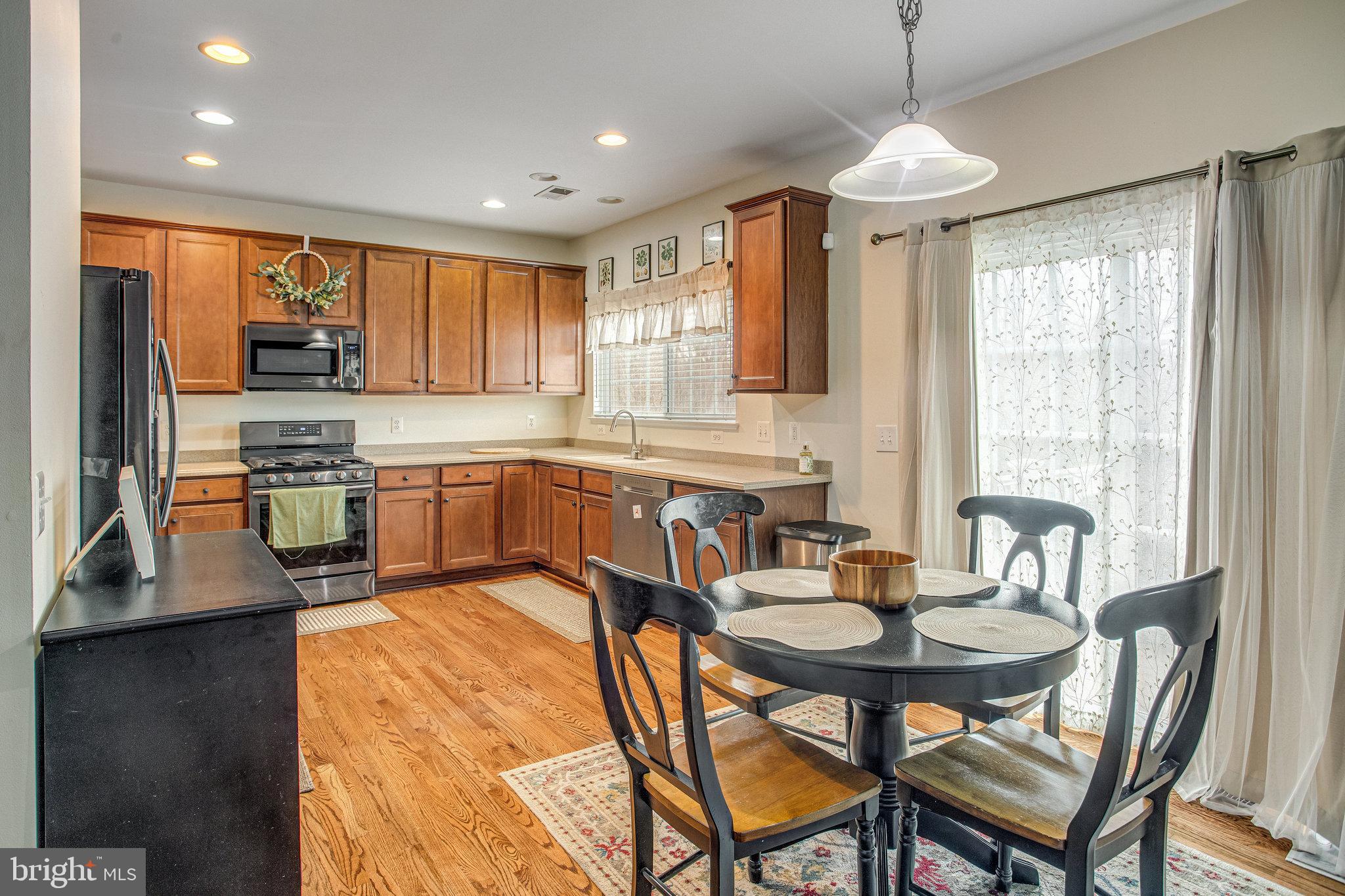 4287 Meyers Road Triangle, VA 22172 - Photo 12 of 51 a kitchen with stainless steel appliances granite countertop a stove a sink a microwave a dining table and chairs with wooden floor