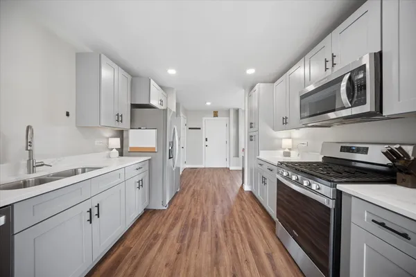 a large kitchen with stainless steel appliances granite countertop a stove a sink dishwasher and a microwave oven with large wooden cabinets