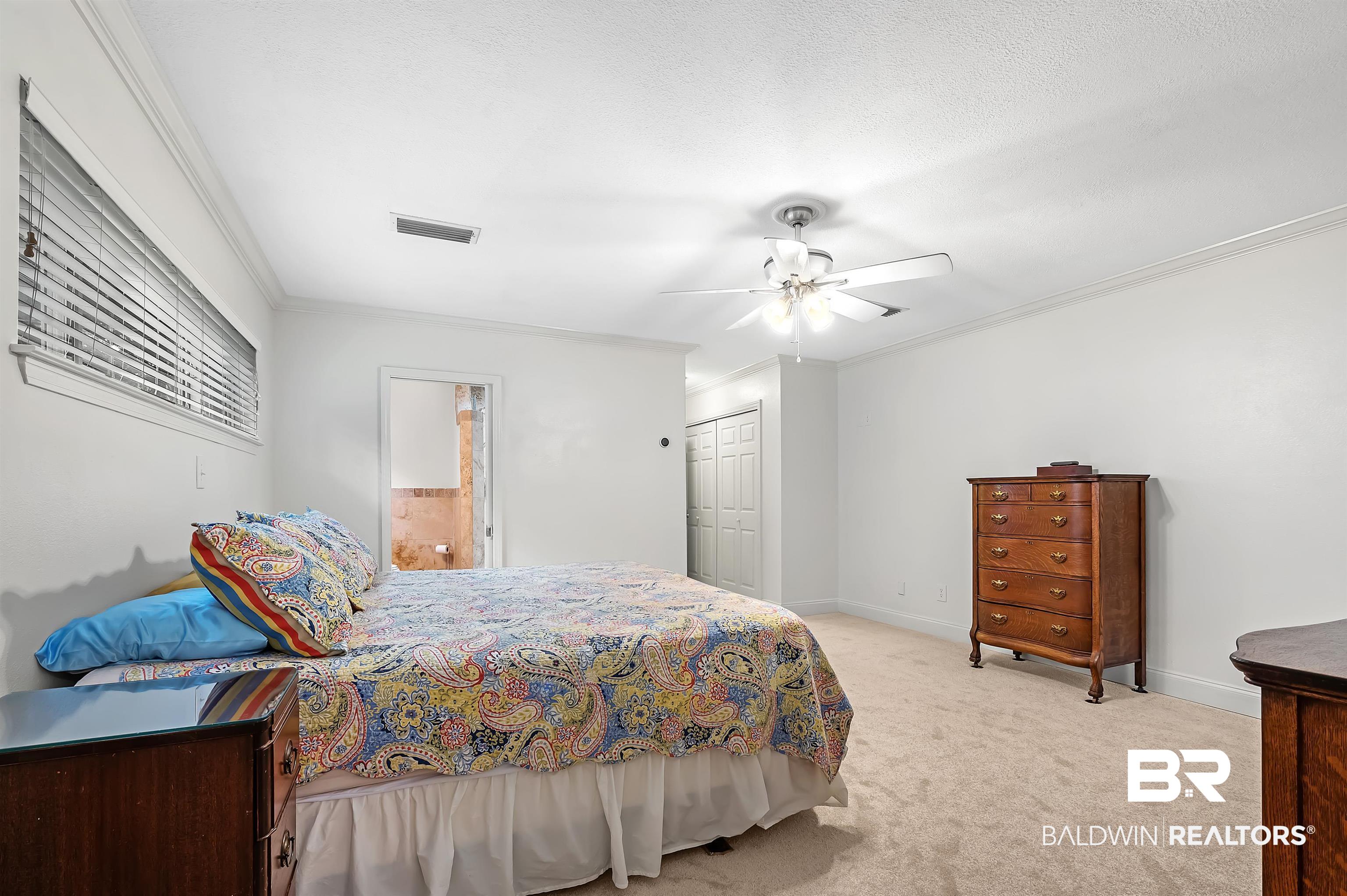 104 James Circle Daphne, AL 36526 - Photo 44 of 62 Bedroom with ornamental molding, light colored carpet, a closet, and ceiling fan