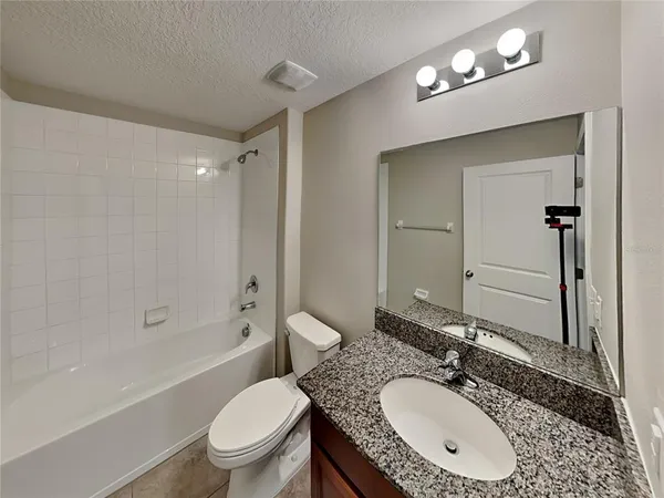 a bathroom with a granite countertop sink a toilet a mirror and shower