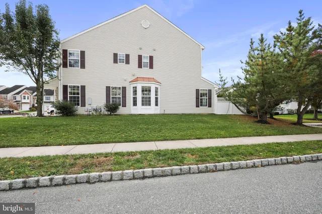 a view of a white house next to a yard with big trees