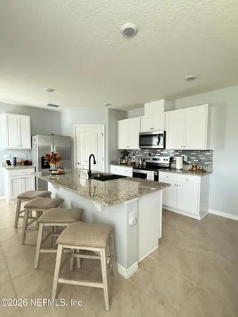 a kitchen with stainless steel appliances granite countertop a stove top oven a sink a dining table and chairs