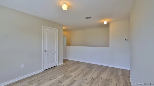 a view of an empty room with wooden floor and windows