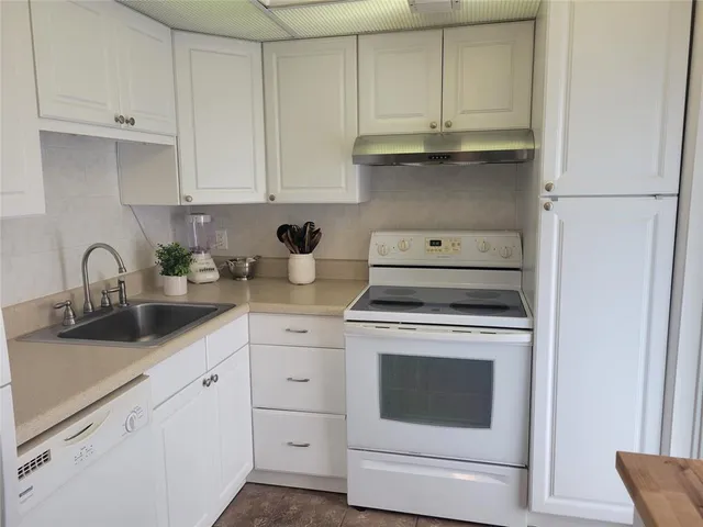 a kitchen with white cabinets and appliances