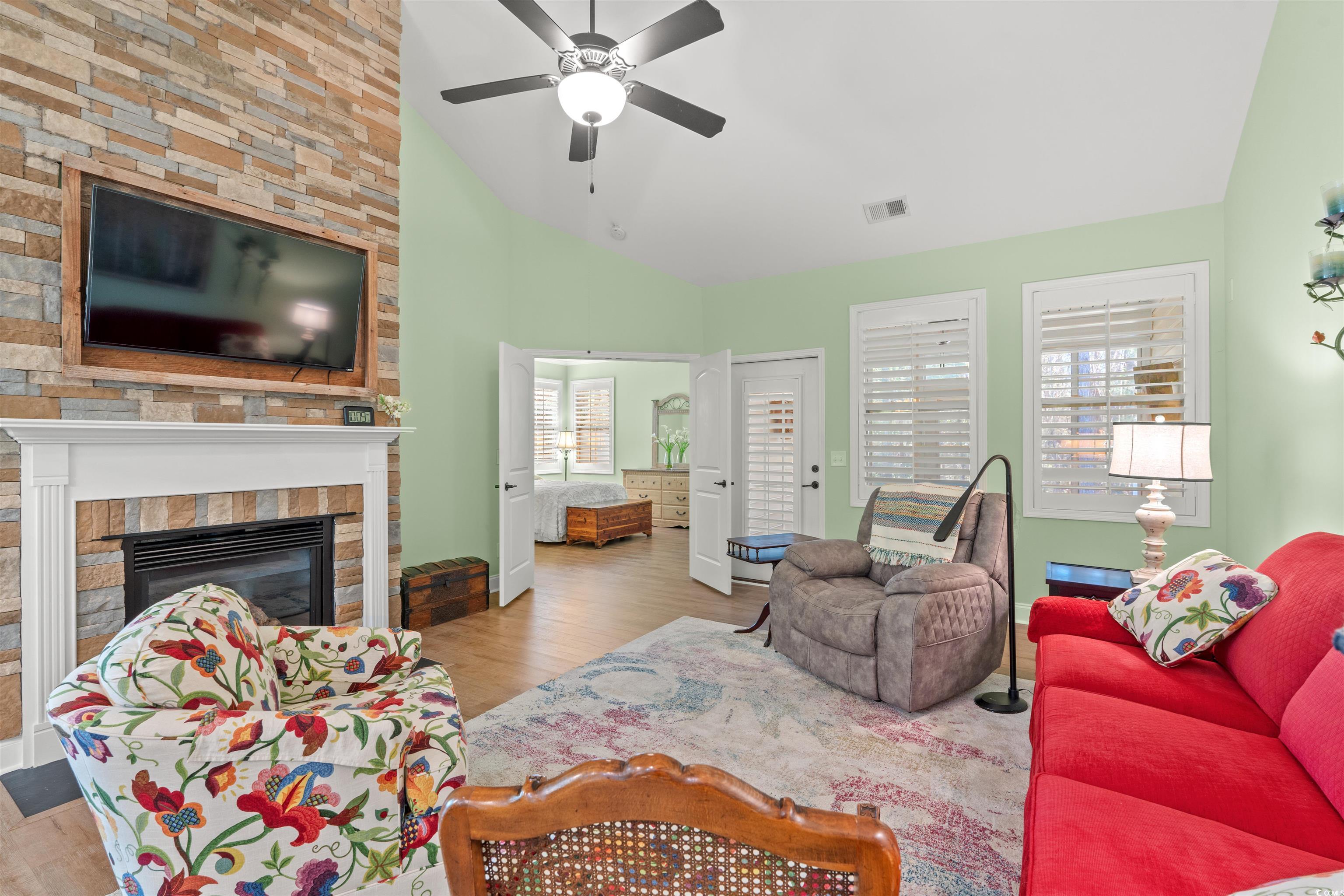 570 Botany Loop, Unit 570 Murrells Inlet, SC 29576 - Photo 15 of 36 Living room featuring vaulted ceiling, visible vents, a ceiling fan, a fireplace, and wood finished floors