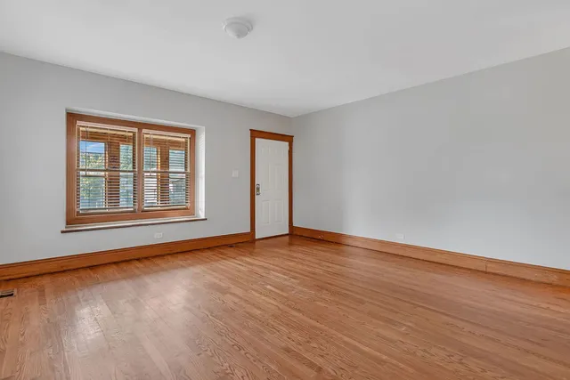 a view of an empty room with window and wooden floor
