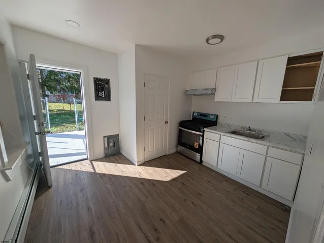 a kitchen with granite countertop wooden floors and white stainless steel appliances