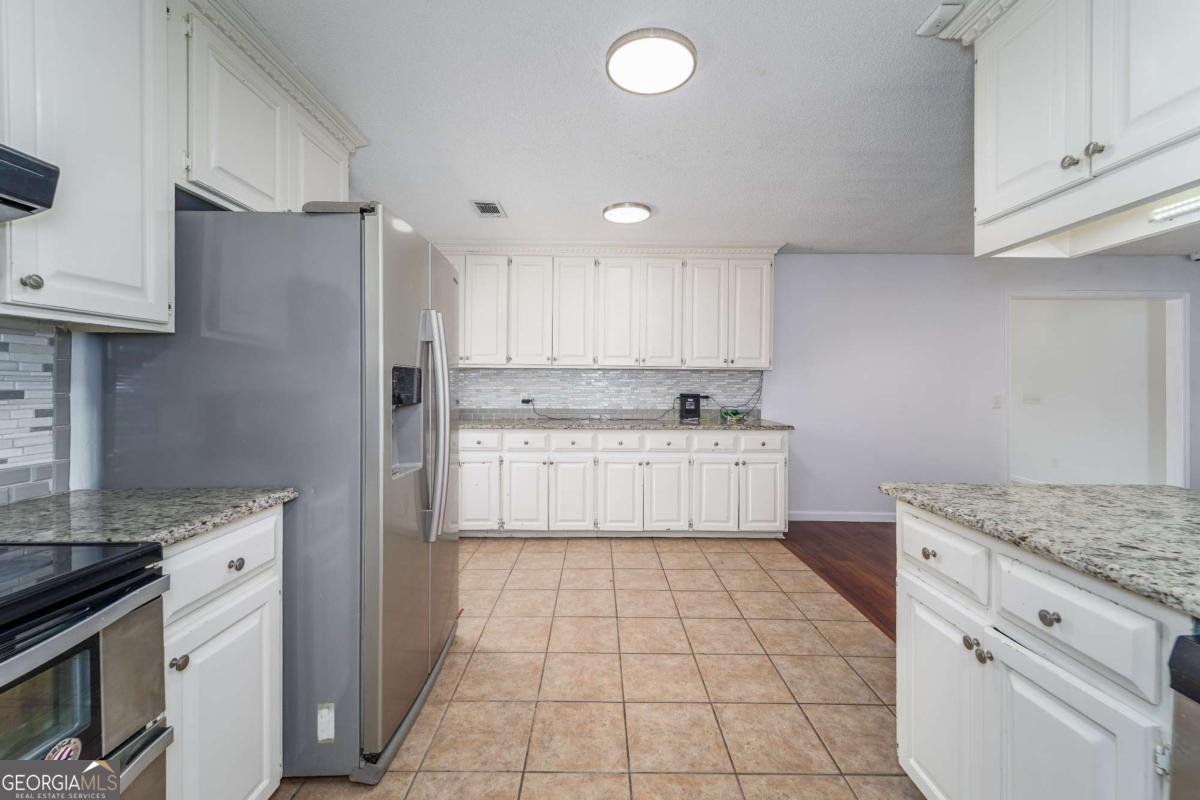 301 Ridge Lane Douglas, GA 31533 - Photo 13 of 26 a kitchen with stainless steel appliances granite countertop a sink a stove a refrigerator and white cabinets