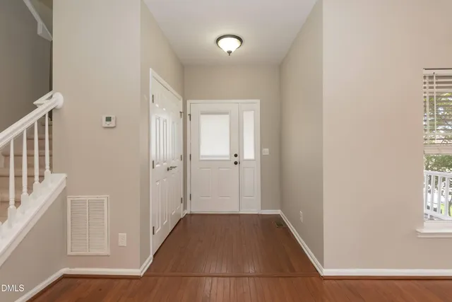 a view of a hallway with wooden floor and a bathroom