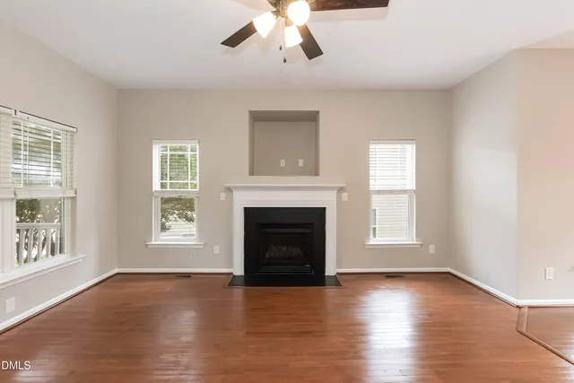 an empty room with windows fireplace and wooden floor