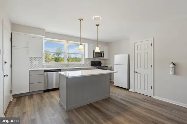 a large kitchen with kitchen island a white counter space a sink and a window