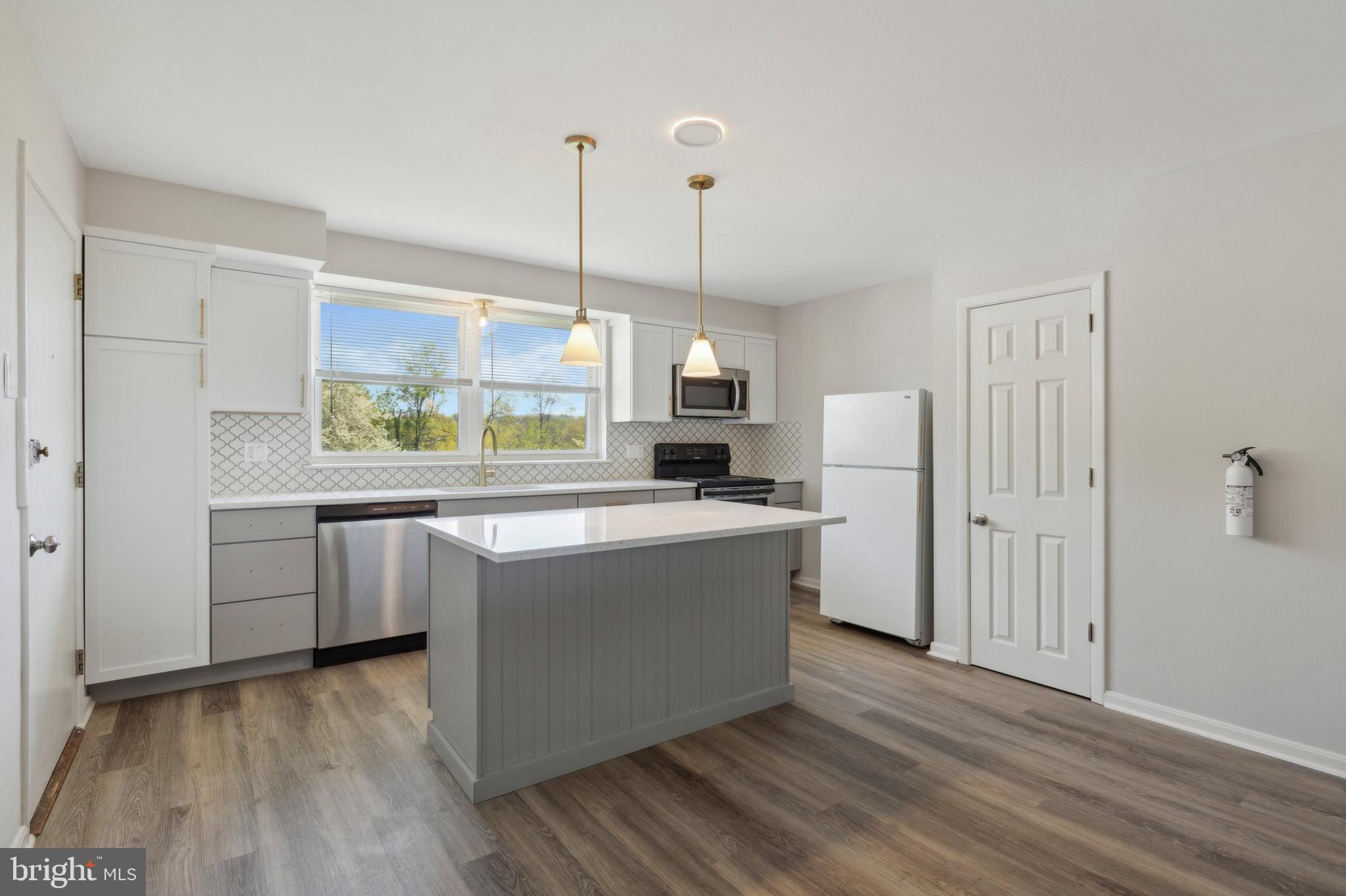 a large kitchen with kitchen island a white counter space a sink and a window