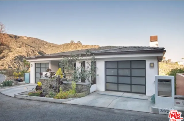 a view of a house with a small yard and potted plants