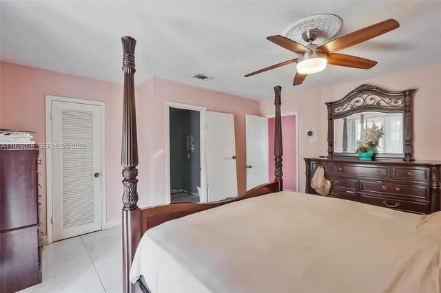 a bedroom with a bed ceiling fan and a large mirror