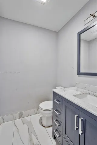 a bathroom with a granite countertop toilet and sink