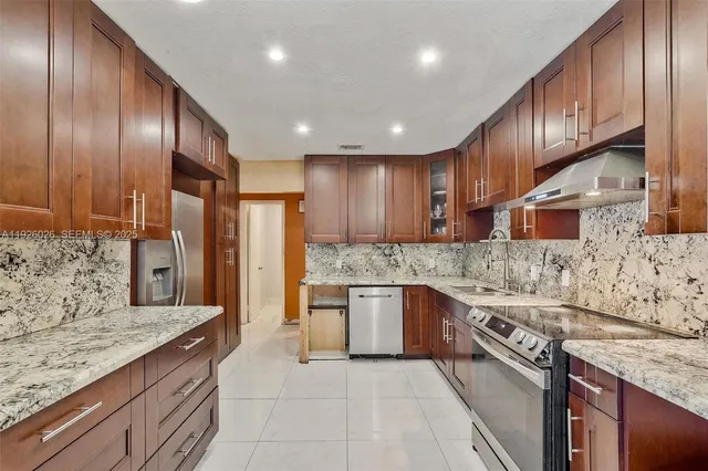 a large kitchen with stainless steel appliances granite countertop a sink stove and refrigerator