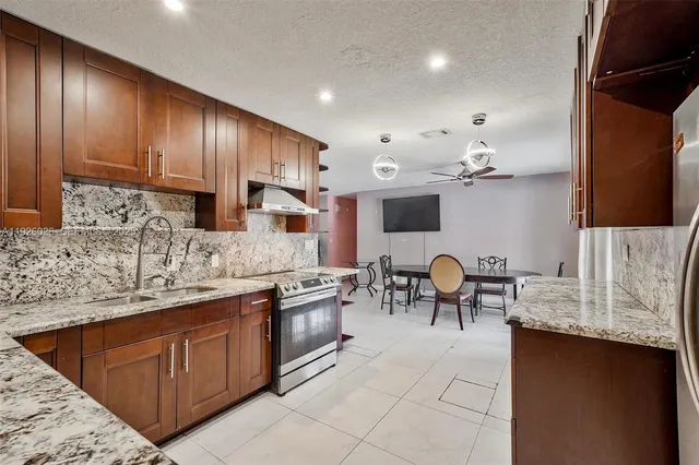 a kitchen with stainless steel appliances granite countertop sink stove top oven and cabinets