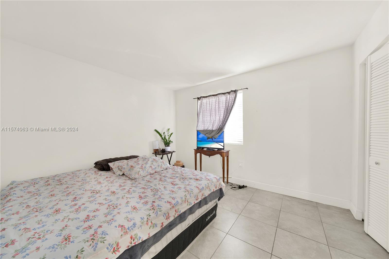 10810 Northwest 7th Street, Unit 6B Miami, FL 33172 - Photo 19 of 19 a bedroom with a bed and a table in it