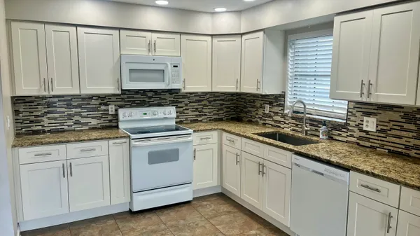 a kitchen with granite countertop white cabinets and white appliances