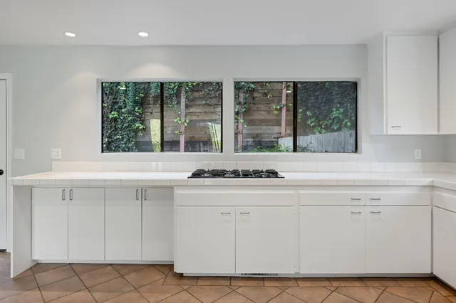 a kitchen with white cabinets and window