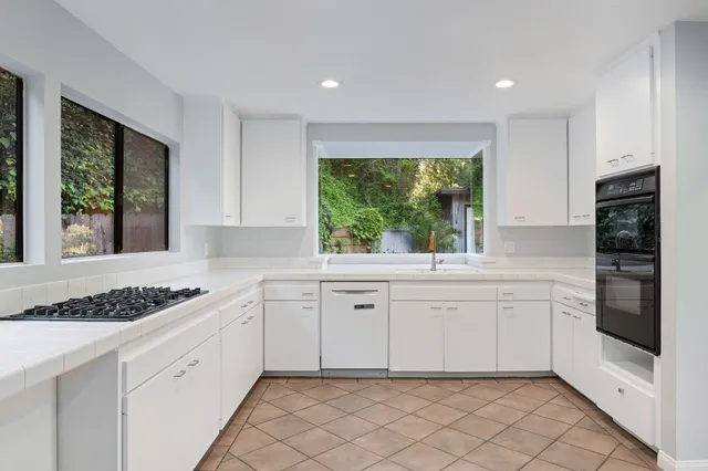 a kitchen with white cabinets and a window