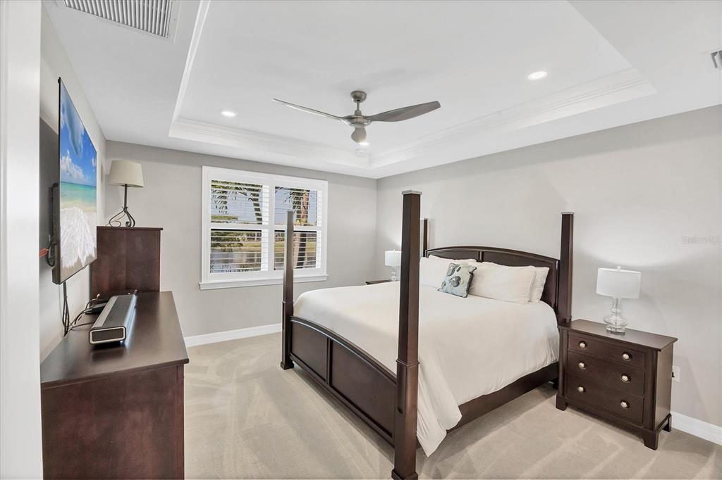 13057 Rinella Street Venice, FL 34293 - Photo 45 of 85 a large bedroom with a bed and a flat tv screen on the dresser