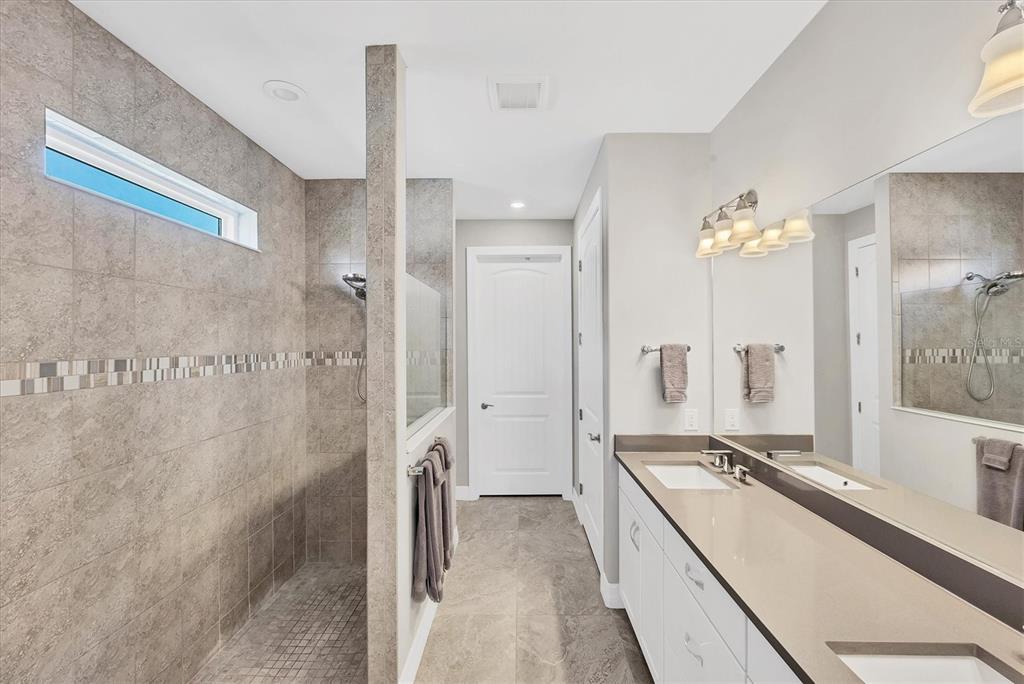 13057 Rinella Street Venice, FL 34293 - Photo 48 of 85 a bathroom with a double vanity sink a mirror and a shower