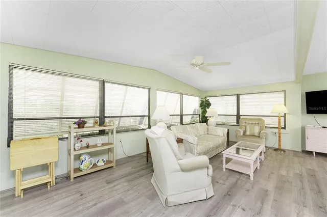 a living room with furniture floor to ceiling window and wooden floor