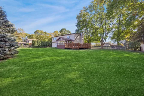 a view of a house with a big yard and large trees