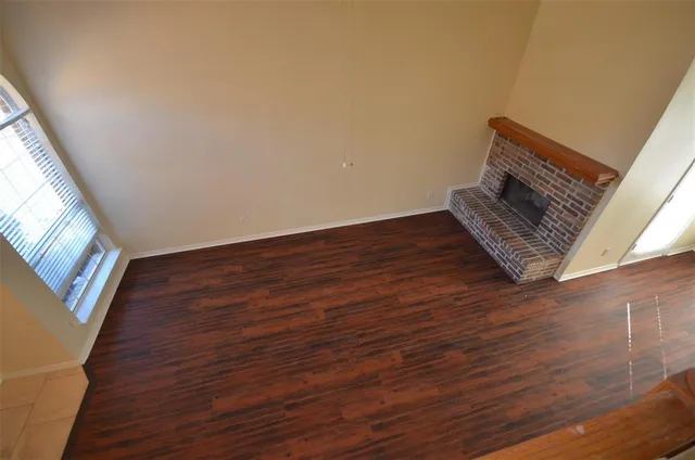 a view of an empty room with wooden floor and stairs