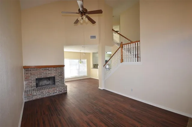 a view of an empty room with wooden floor fireplace and a window