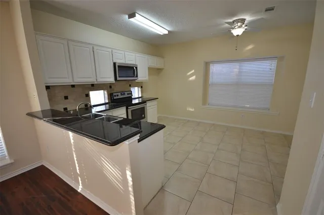 a kitchen with stainless steel appliances granite countertop a stove a sink and a microwave