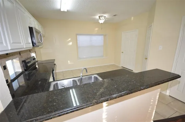 a kitchen with granite countertop a sink and a stove