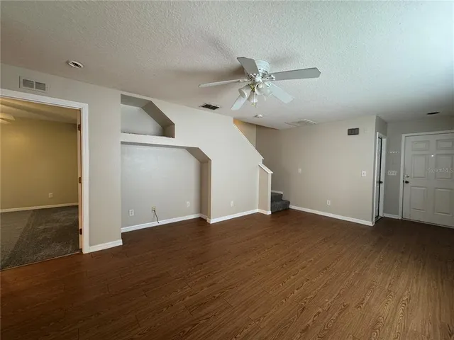 an empty room with wooden floor closet and windows