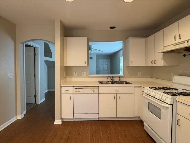 a kitchen with white cabinets sink and stove