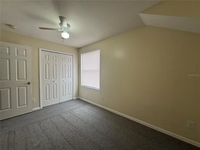 a view of an empty room with a chandelier fan