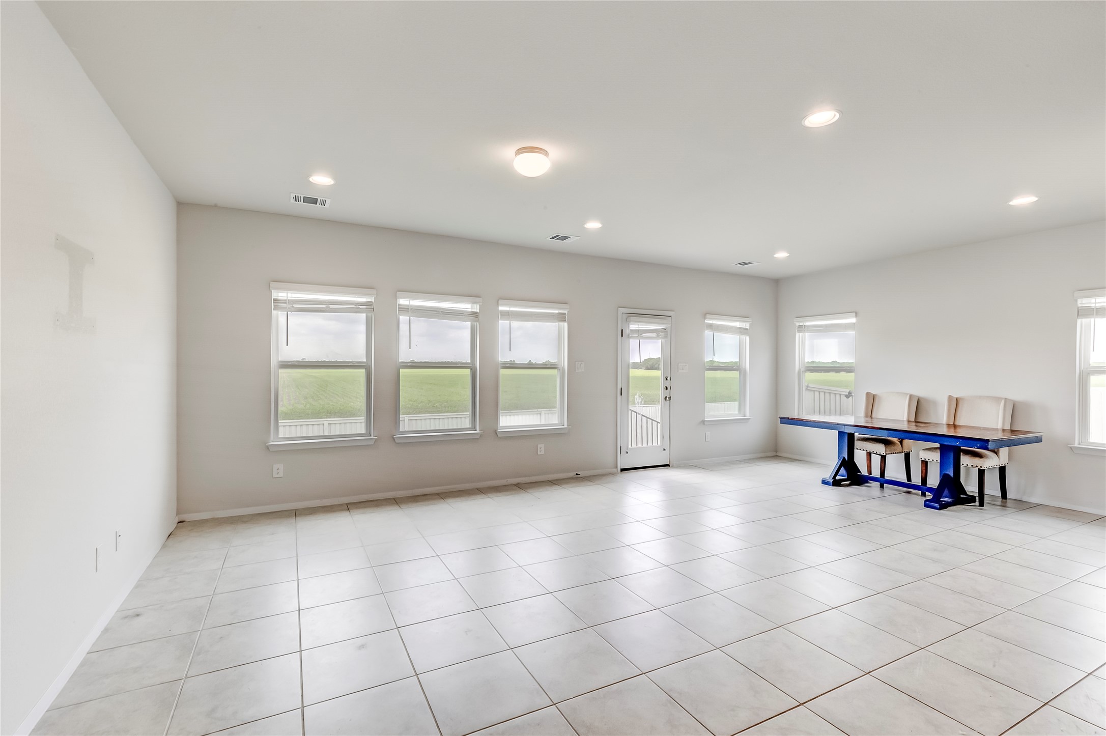 2721 Winding Creek Road Kyle, TX 78640 - Photo 6 of 27 Spacious interior area featuring light-toned tile flooring, recessed ceiling lighting, multiple windows with blinds, and a rear door with a full-view glass panel