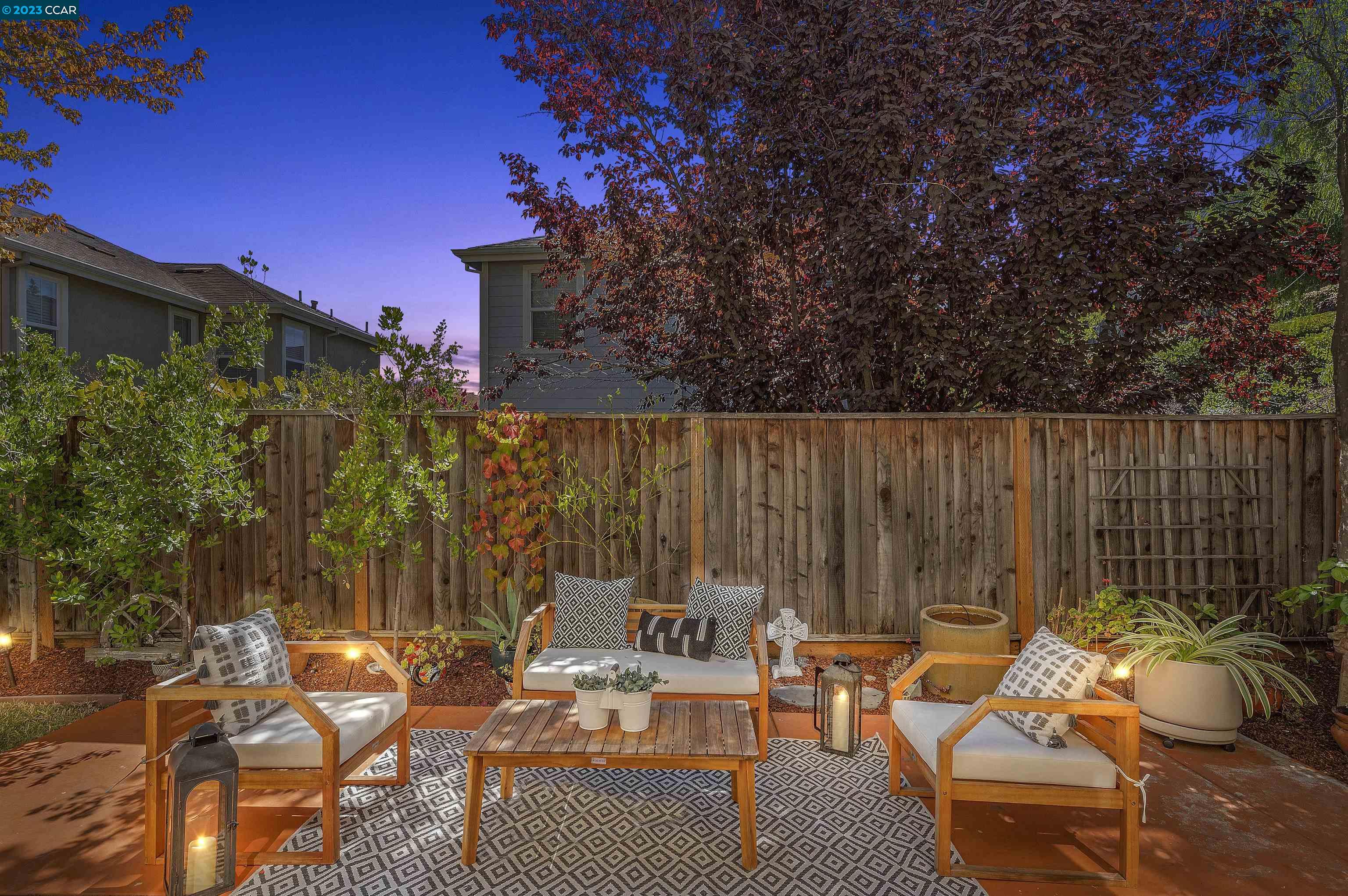 a view of a patio with couches and table and chairs with wooden fence