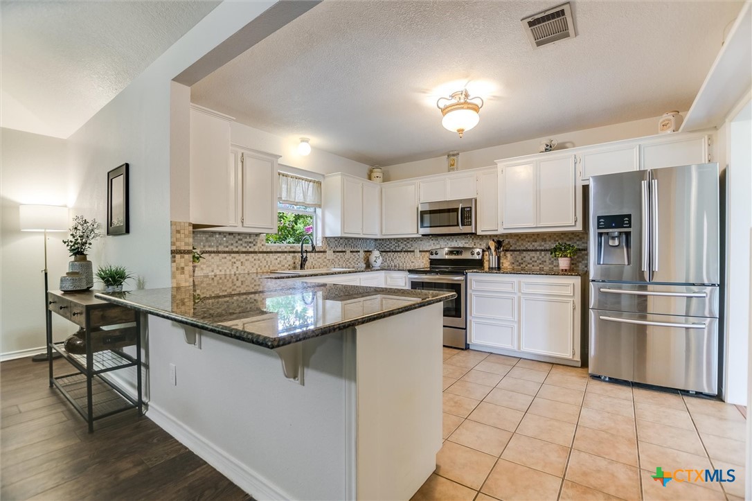 60 Crazy Cross Road Wimberley, TX 78676 - Photo 7 of 20 Kitchen with stainless steel appliances, abundant cabinetry, tile flooring, and breakfast bar.