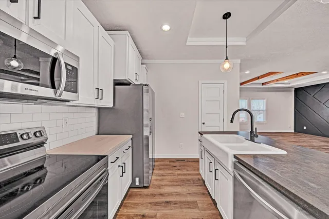 a kitchen with stainless steel appliances granite countertop a sink a counter space and wooden floor
