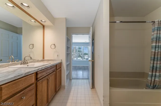 a bathroom with a granite countertop sink mirror and a bathtub