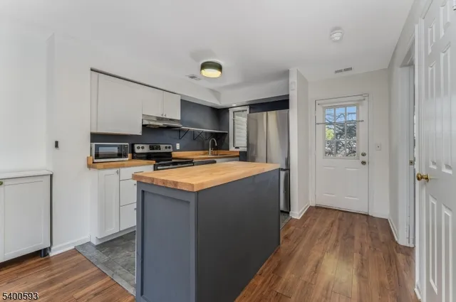 a kitchen with kitchen island wooden floors and refrigerator