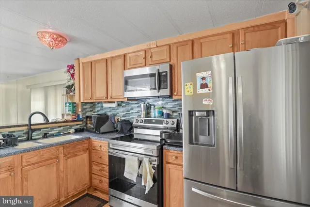 a kitchen with stainless steel appliances a refrigerator sink and microwave